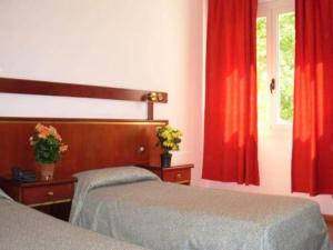 a bedroom with two beds and red curtains at Hotel Vienna in Marghera