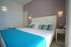 een slaapkamer met een groot wit bed met blauwe lakens bij Nicolaus Prime Il Gabbiano Hotel in Pulsano