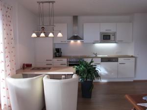a kitchen with white cabinets and a table and chairs at Apartment Bachmann in Oberau