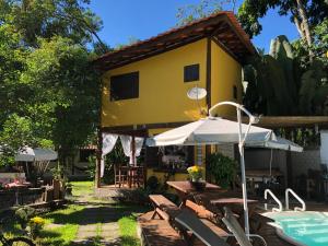 a yellow house with a pool and chairs and an umbrella at Pousada Estalagem Paraty in Paraty