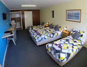 um quarto com 2 camas e uma secretária com uma secretária. em Turn-in Motel em Warrnambool