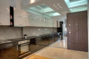 a large kitchen with white cabinets and a brown door at Apartment in Glyfada Center in Athens