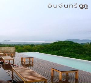 a wooden deck with benches and a swimming pool at Inchantreedoopool in Kanchanaburi City