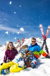 un grupo de tres personas sentadas en la nieve en Résidence Goélia Les Chalets de Super-Besse, en Super Besse