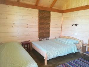 een slaapkamer met 2 bedden in een houten hut bij Rozītes in Cesvaine