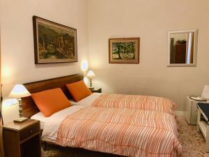 ローマにあるNori Guest Houseのベッドルーム1室(オレンジ色の枕が備わるベッド2台付)