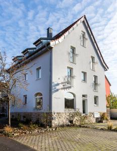 a white building with windows and a tree at Hotel am Rokokogarten in Veitshöchheim