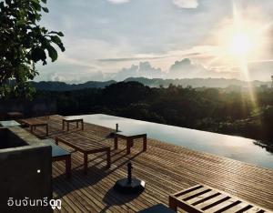 a deck with tables and a pool with a view at Inchantreedoopool in Kanchanaburi City