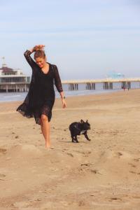 a woman running on the beach with a black dog at ABC Hotel in Blankenberge