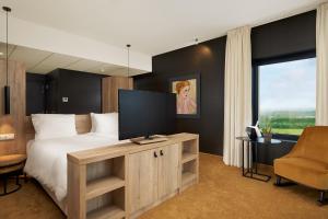 a bedroom with a large bed with a flat screen tv at Van Der Valk Luxembourg Arlon in Arlon