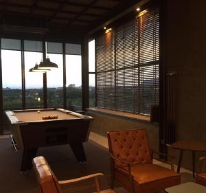 a room with a pool table and chairs and windows at Inchantreedoopool in Kanchanaburi City