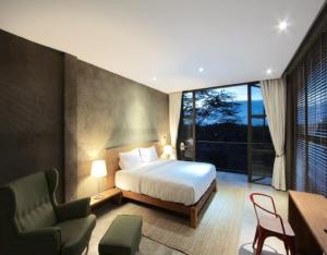 a bedroom with a bed and a desk and a chair at Inchantreedoopool in Kanchanaburi City