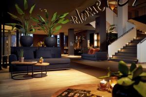a living room with a blue couch and potted plants at Van Der Valk Luxembourg Arlon in Arlon