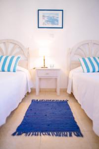 a bedroom with two beds and a blue rug at Dunas do Alvor - Torralvor in Alvor
