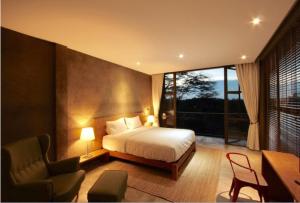a bedroom with a bed and a desk and a chair at Inchantreedoopool in Kanchanaburi City