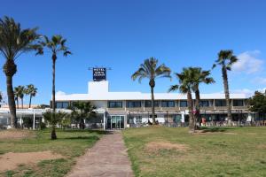 a building with palm trees in front of it at Hotel Costa Azahar in Grao de Castellón