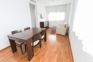 - une salle à manger avec une table, des chaises et un canapé dans l'établissement Domocenter Apartamentos Turísticos, à Bormujos
