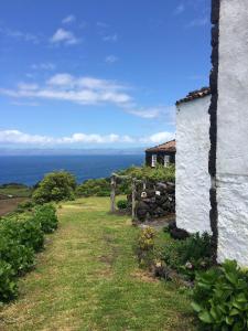 uma casa numa colina com o oceano ao fundo em Casa Da Lava em São Roque do Pico
