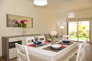 uma sala de jantar com uma mesa com cadeiras e flores em Apartamento luxo e sossego em Albufeira