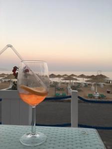 Holiday Rooms Domina Coral Bay في شرم الشيخ: كوب من النبيذ على طاولة مطلة على شاطئ