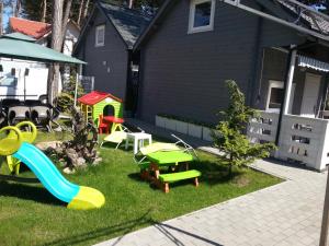 un patio trasero con un parque infantil con un tobogán en Domki Finezja en Dziwnówek