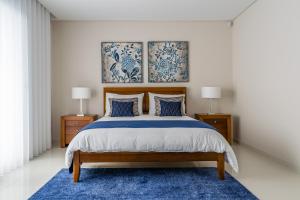 Ein Schlafzimmer mit einem Bett, einem blauen Teppich und zwei Lampen in der Unterkunft RR House in Ribeira Quente