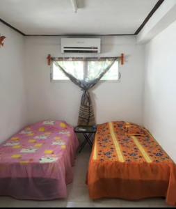 two beds in a room with a window at Casa Colonial Centro in Mérida