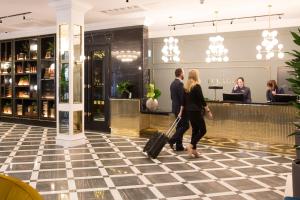 un hombre y una mujer caminando por el vestíbulo de un hotel con su equipaje en Iveagh Garden Hotel en Dublín