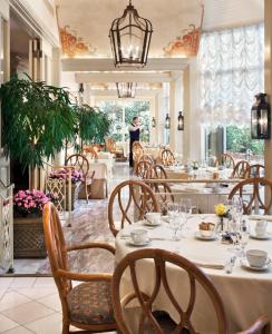 a restaurant with white tables and chairs and a man in the background at The Windsor Court in New Orleans