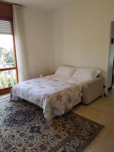 ヴァレーゼにあるAppartamento Villa Adrianaのベッドルーム1室(ベッド1台、窓、ラグ付)