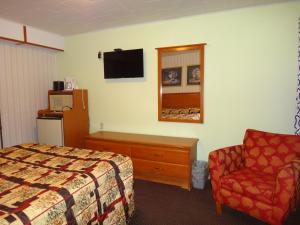 a hotel room with a bed and a chair at Pine Ridge Motel in Dodgeville