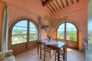 a kitchen with two windows and a table with chairs at Agriturismo Villa Felice in Volterra