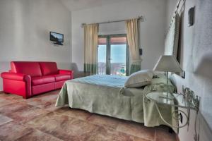 a bedroom with a bed and a red chair at Country House Vignola Mare in Aglientu