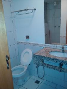 a bathroom with a toilet and two sinks at Águas da Serra Apart in Rio Quente