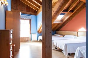 Pensión la Campanilla في La Penilla: سريرين في غرفة ذات جدران زرقاء وسقوف خشبية