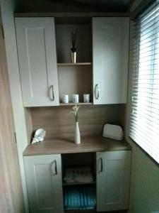 a kitchen with white cabinets and a vase with flowers in it at 11 Burnside Lodge in Auchterarder