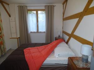 um quarto com uma cama com um cobertor vermelho em Gite de l'étang em Belval-en-Argonne