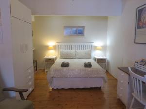 a bedroom with a white bed and two night stands at Dempsey's Self-Catering Guest House in Port Elizabeth