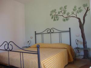 a bedroom with a bed with a tree on the wall at Agriturismo La Sarticola in Luni