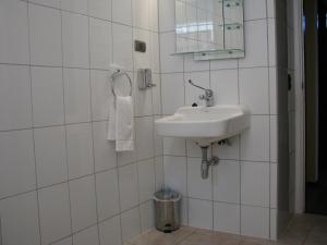 a white tiled bathroom with a sink and a mirror at Portal Austral in Puerto Montt