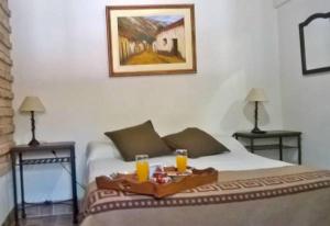 a bedroom with a bed, a table, and a painting on the wall at Hostal Tierra de Vinos in Cafayate