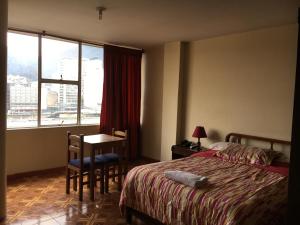 a bedroom with a bed and a table and a window at Hotel Manila Plaza in Bogotá