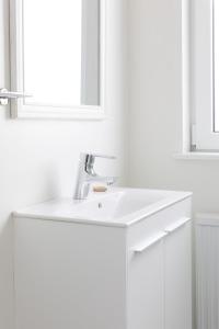 La salle de bains blanche est pourvue d'un lavabo et d'un miroir. dans l'établissement Guesthouse Baegisa, à Akureyri