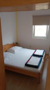 a bedroom with a bed with two sheets and a window at Apartments Ante in Vir