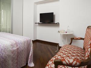 ein Schlafzimmer mit einem Bett, einem Stuhl und einem TV in der Unterkunft Alloggio La Volta in Viterbo