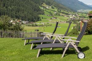 two chairs sitting on top of a field with a valley at Haus Fernblick in Neustift im Stubaital