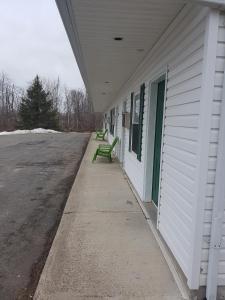 two green benches sitting on the side of a building at Covered Bridge Inn & Suites in Sussex
