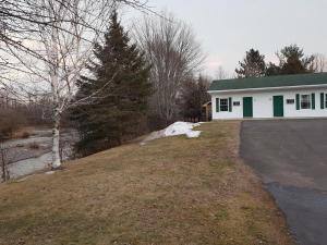 a white house with green doors and a driveway at Covered Bridge Inn in Sussex