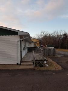 - un bâtiment blanc avec une terrasse couverte à côté d'une clôture dans l'établissement Covered Bridge Inn & Suites, à Sussex