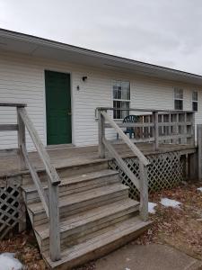 une maison avec une terrasse couverte en bois et une porte verte dans l'établissement Covered Bridge Inn & Suites, à Sussex